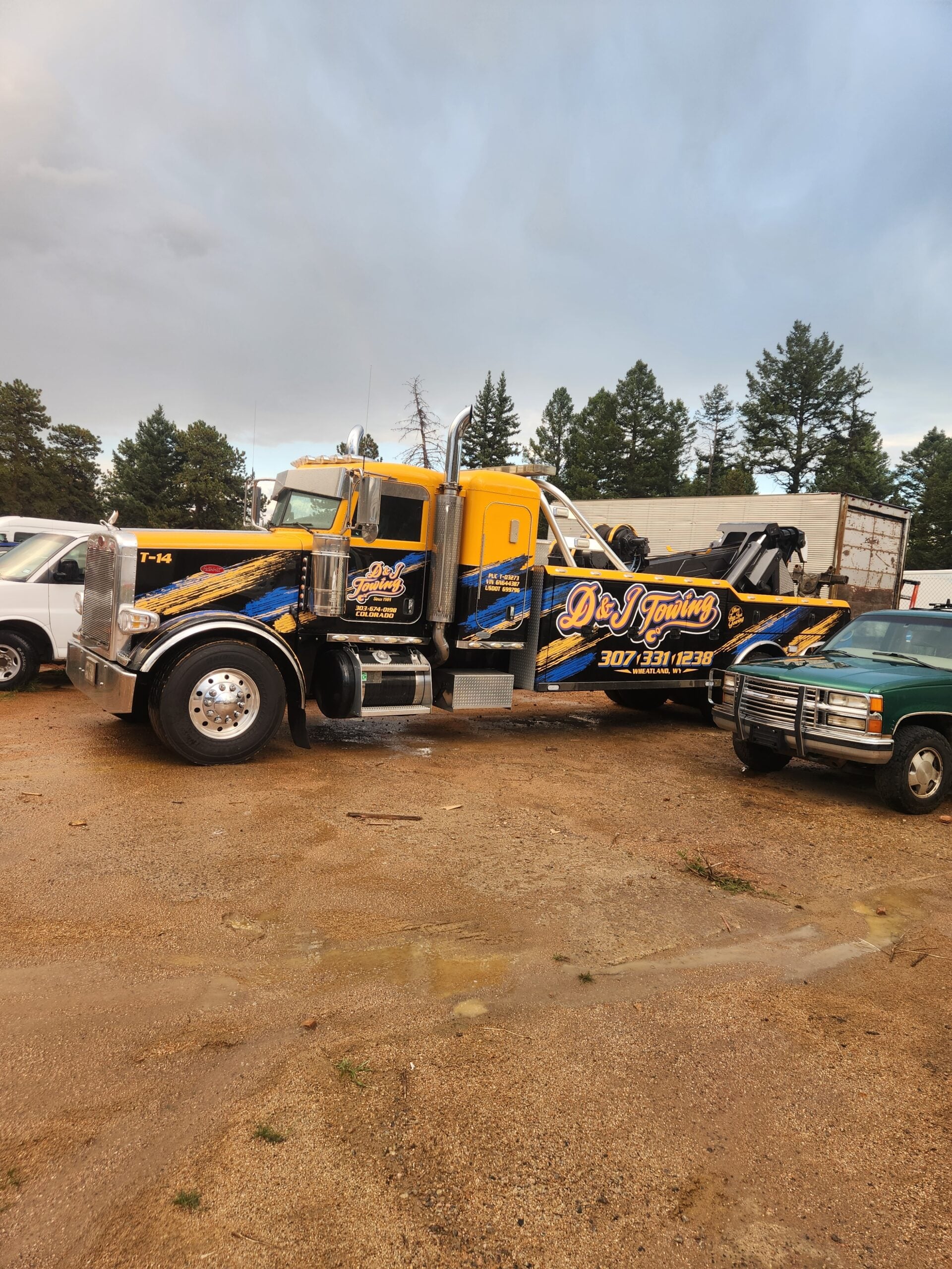 D&J Towing heavy-duty wrecker in the gold and blue D&J wrap, parked at the yard