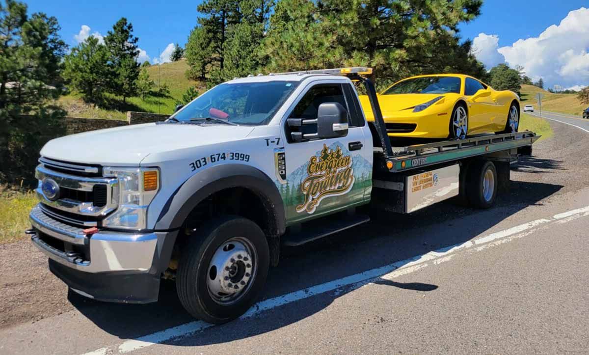 White Ford flatbed carrying a yellow sports car on a mountain road