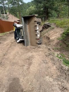 Tipped equipment lying on a dirt slope