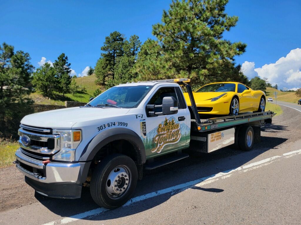 D&J tow truck with a yellow car loaded on the back, parked at the roadside