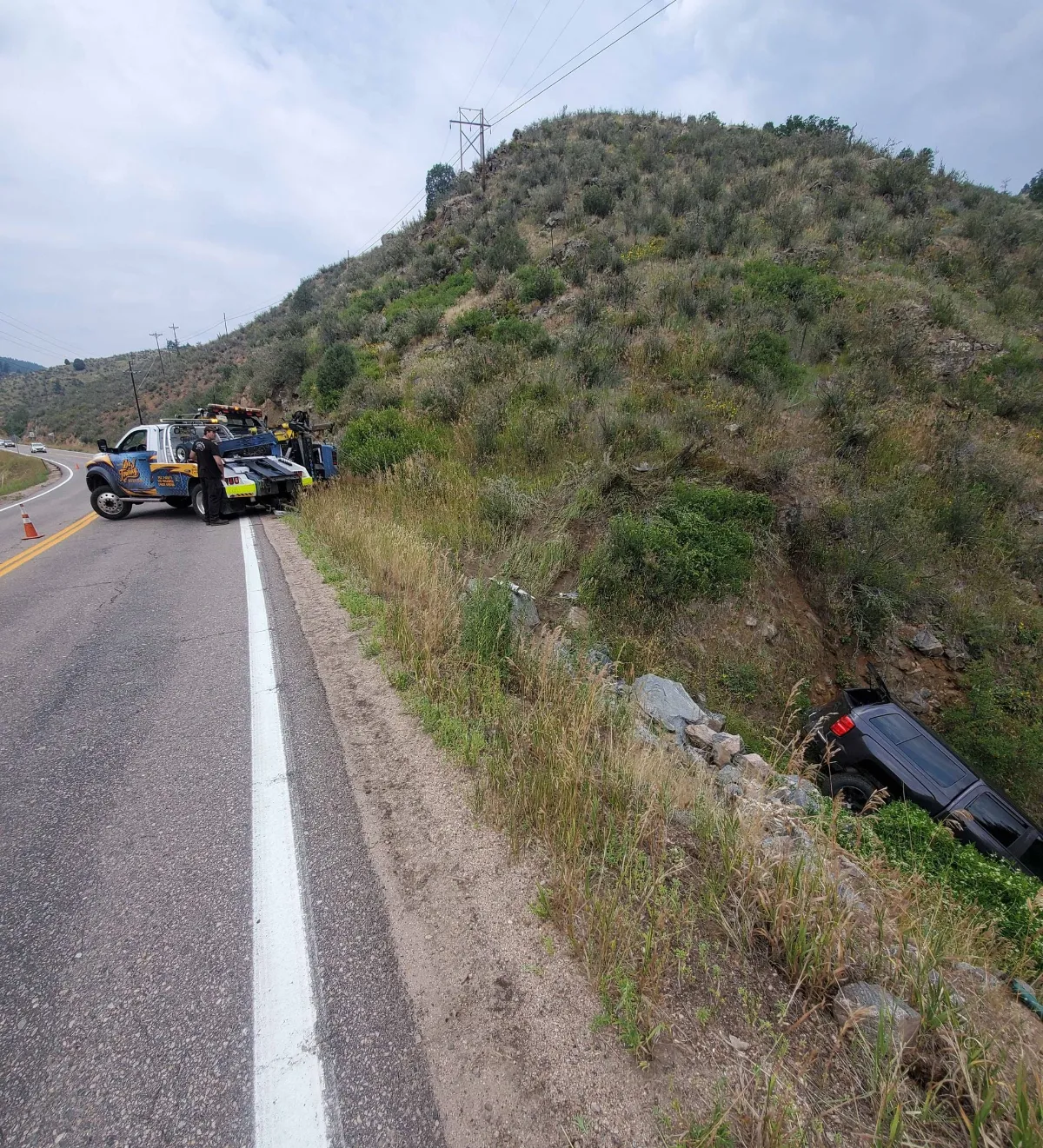 D&J wrecker on a mountain road pulling a vehicle up from an embankment